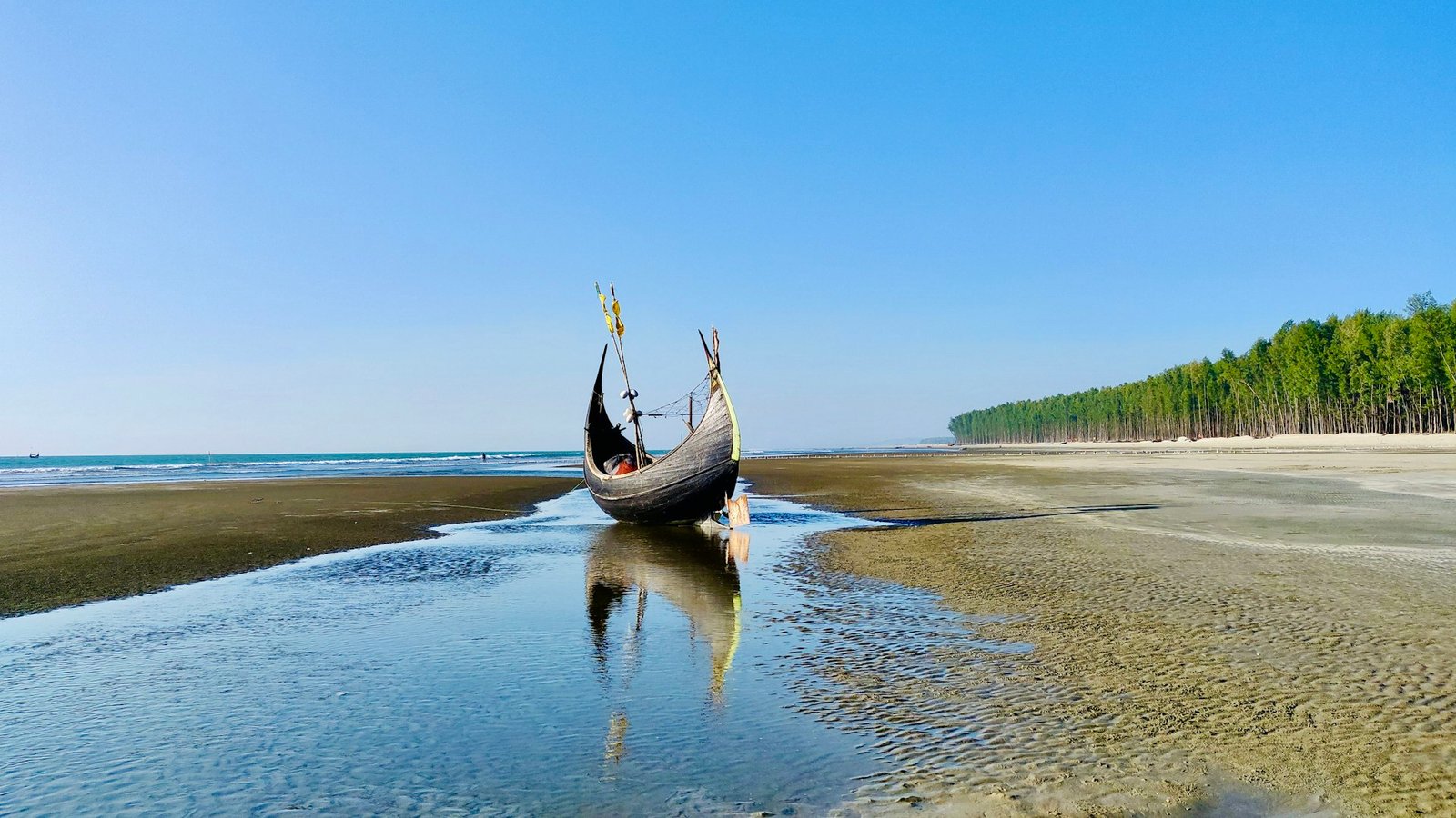A fishing boat on a wide sandy beach