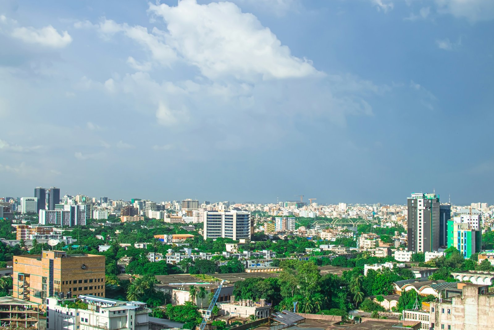 Dhaka city skyline with green trees under a blue sky