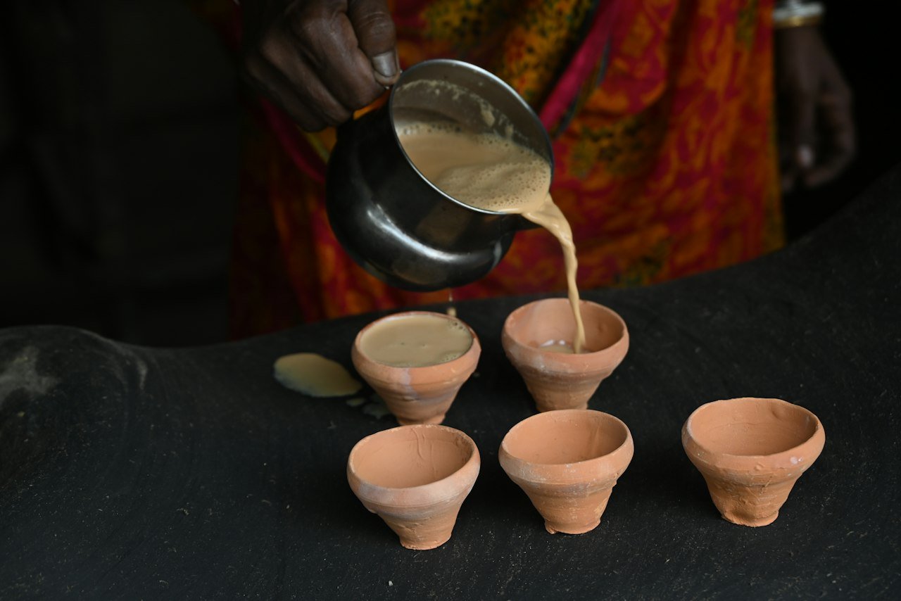 Milk tea being poured into small clay cups